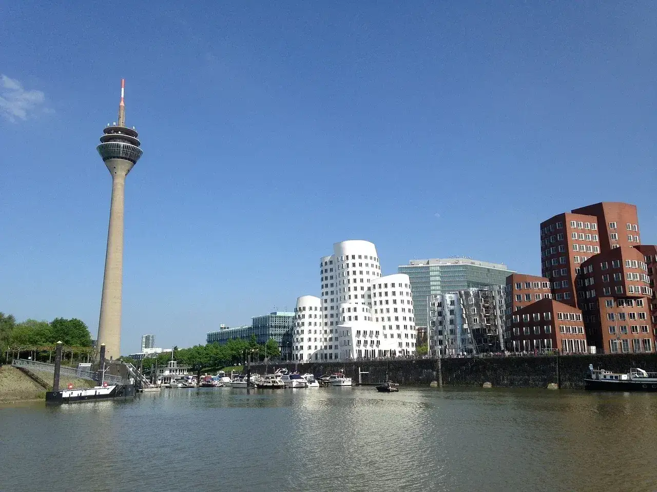 Widok na Ren z wieżą telewizyjną i nowoczesną architekturą, w tym charakterystycznymi białymi budynkami. Dusseldorf atrakcje w pełnej krasie.