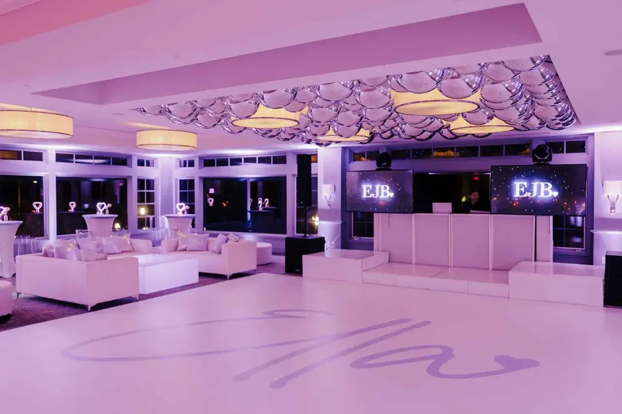 Ein eleganter **partyraum gestalten** mit weißen Sofas, DJ-Pult und Bildschirmen, die