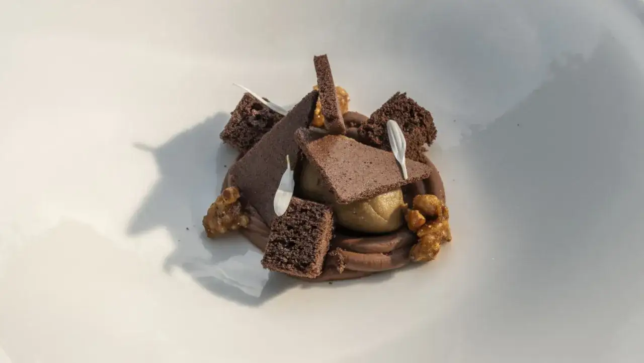 Postre de chocolate con bizcocho, crema y frutos secos. Una obra maestra de texturas de chocolate.
