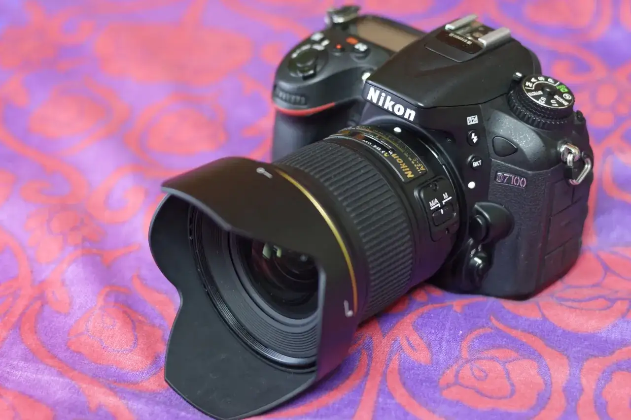 Nikon D7100 z obiektywem AF-S na fioletowym tle z różowymi wzorami. Gotowy do uchwycenia każdej chwili.