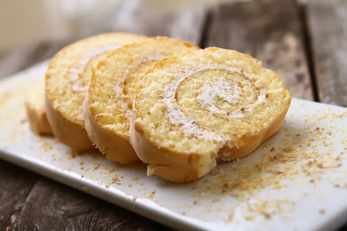 Fette di pasta biscotto perfetta, con crema e spolverata di zucchero a velo, su un piatto bianco.