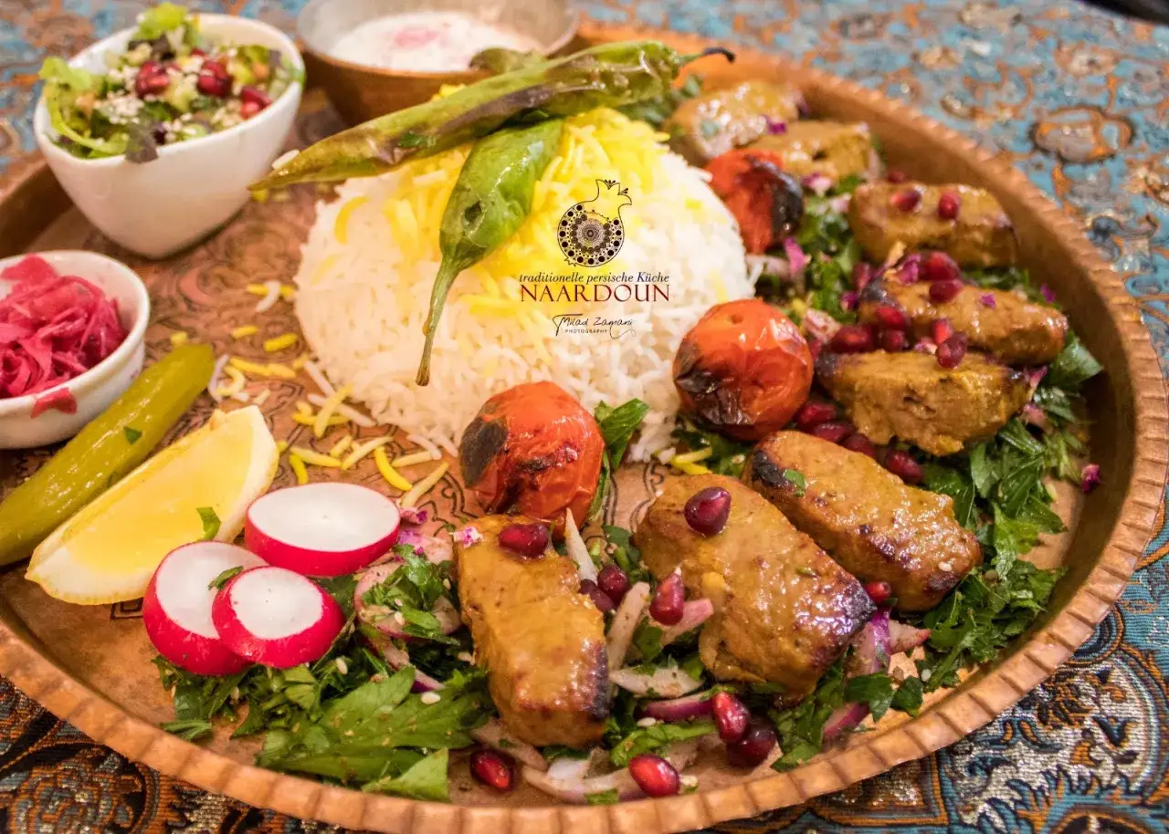 Köstliches persisches Essen im Restaurant Naardoun in Berlin: Reis, gegrilltes Fleisch, Tomaten und frischer Salat.