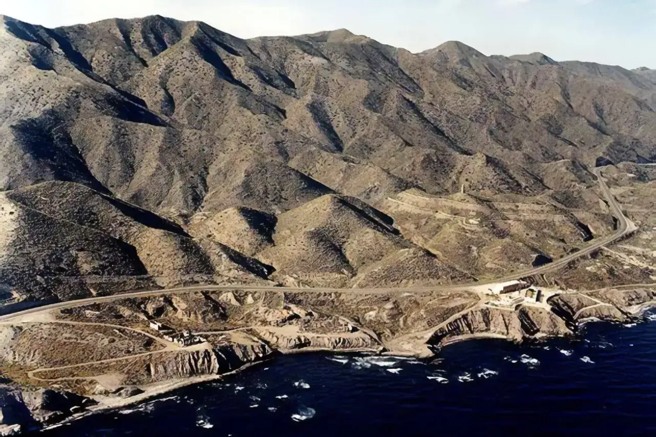 Paisaje árido de montañas y mar en la cala invencible Almería. Una carretera serpentea por la costa rocosa.