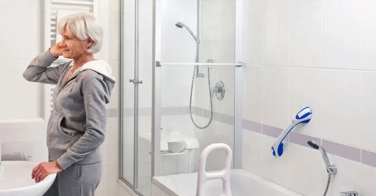 Une femme se prépare dans une salle de bain équipée d'une barre d'appui PMR norme pour plus de sécurité.