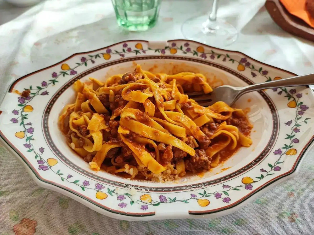 Tagliatelle al ragù, un classico per scoprire dove mangiare a Bologna. Un piatto invitante su un piatto decorato.