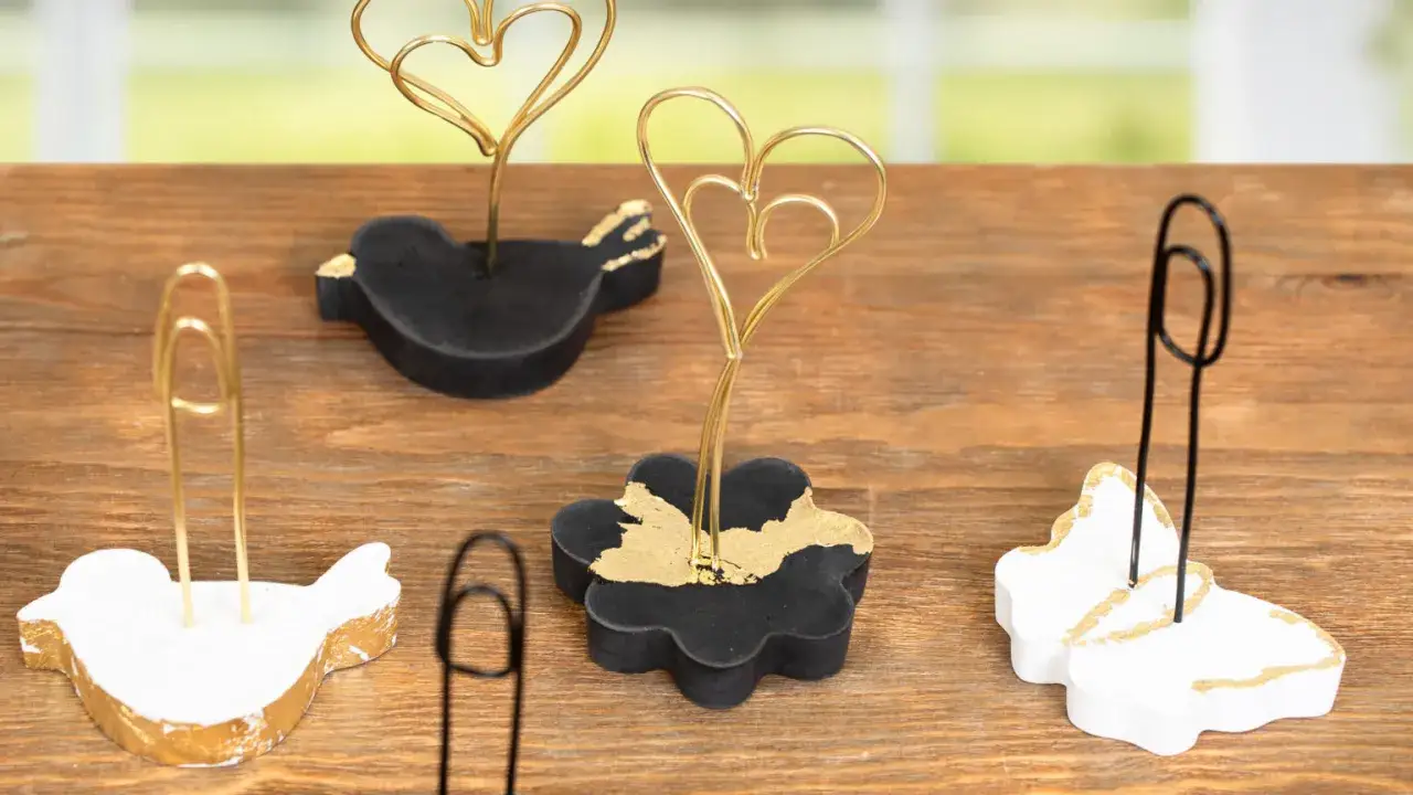 Kreative fotohalter selber machen: V&ouml;gel, Blumen und Schmetterlinge aus Beton mit Goldakzenten, die Fotos oder Karten halten.