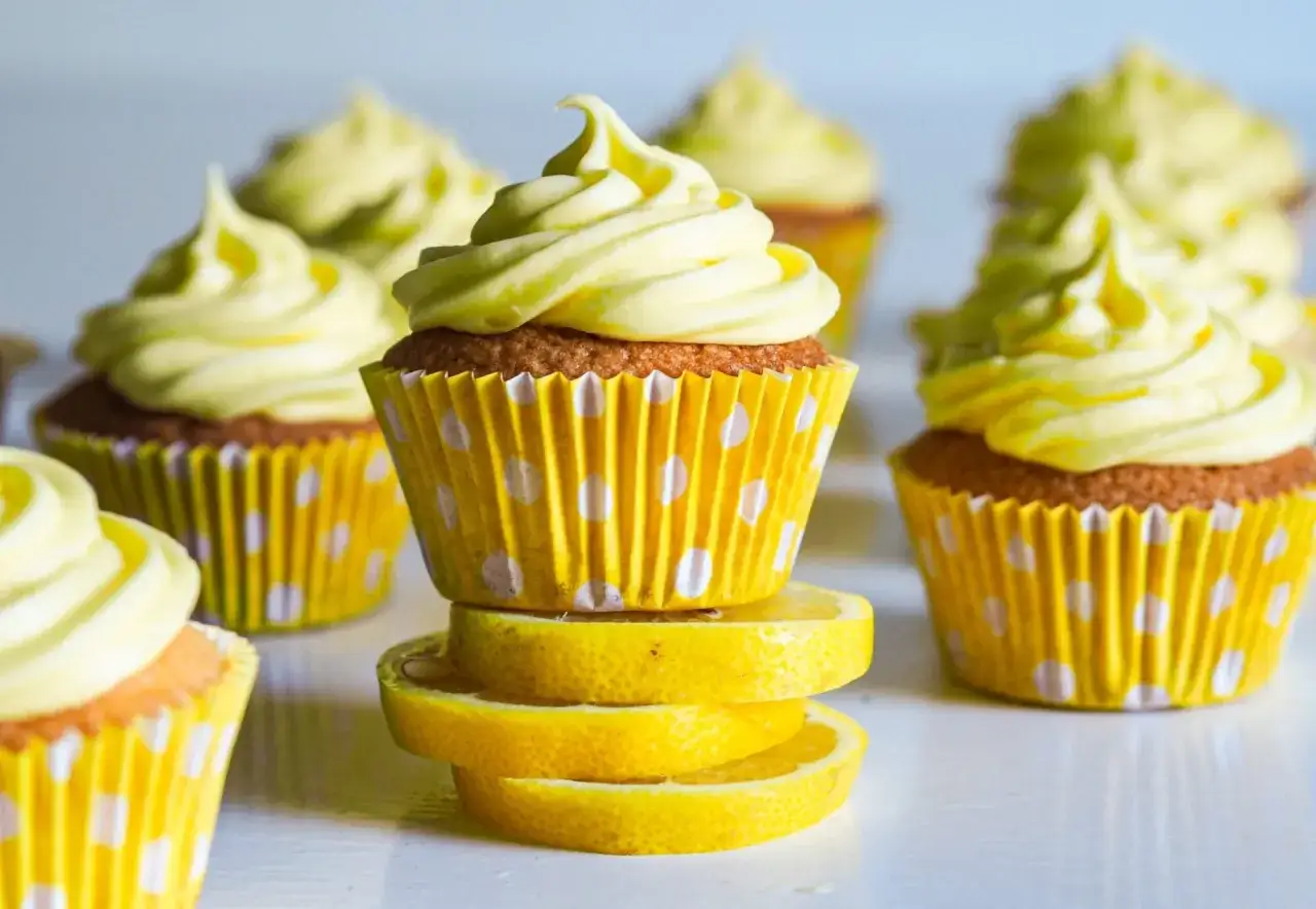 Gula citronmuffins med vit frosting i prickiga formar, inspirerade av ett enkelt citronmuffins recept.