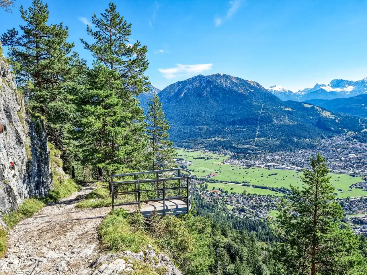 Wanderweg mit Aussichtsplattform &uuml;ber Garmisch-Partenkirchen. Bergpanorama und gr&uuml;ne Wiesen laden zum Wandern ein.