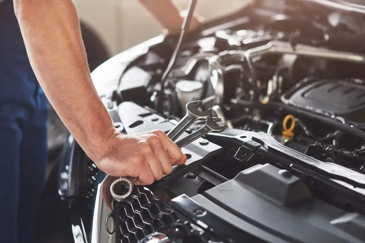 Mecánico revisa el motor de un coche, buscando la causa del traqueteo.