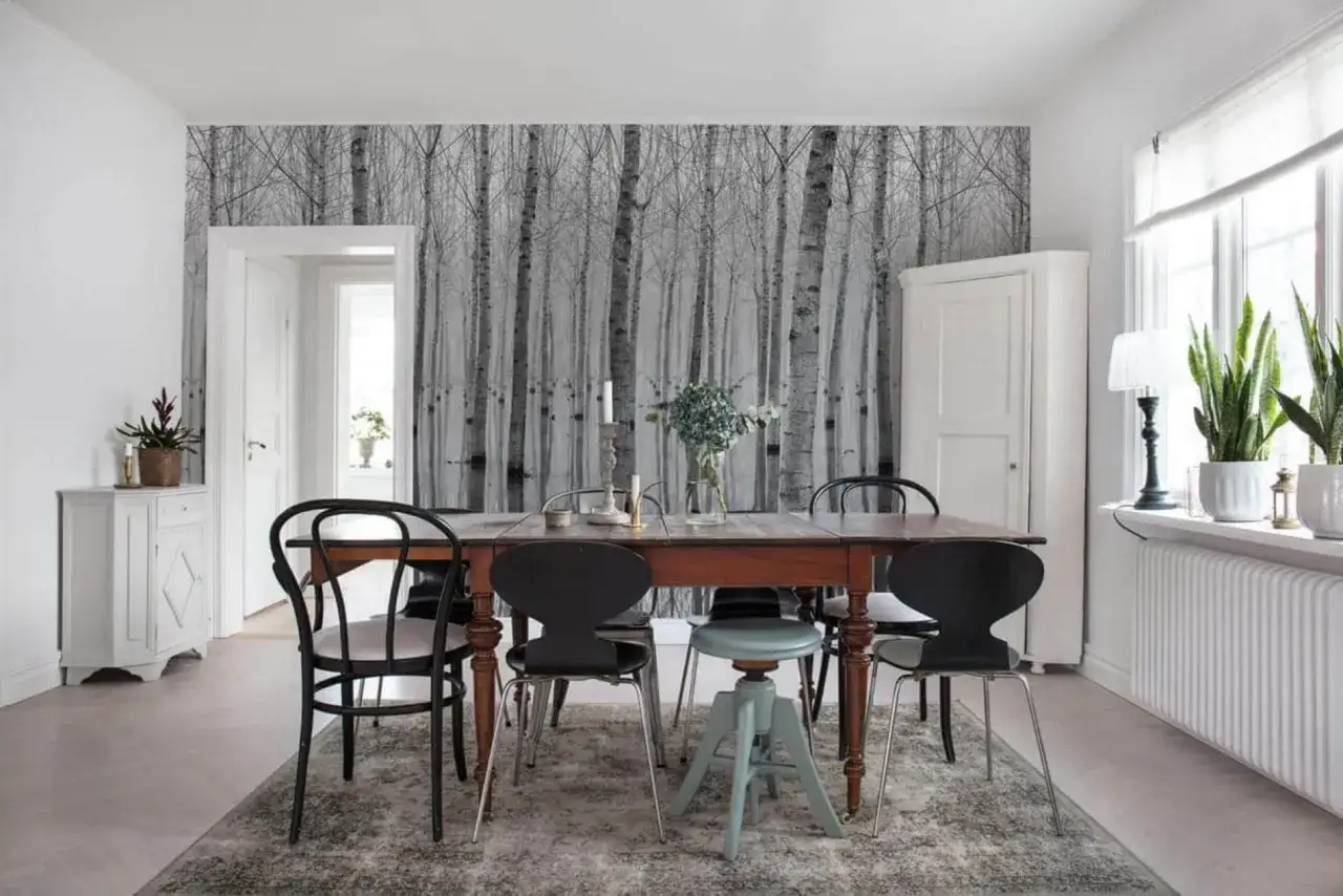 Elegancka fototapeta brzozy w salonie tworzy leśny klimat. Drewniany st&oacute;ł i krzesła dopełniają aranżację.