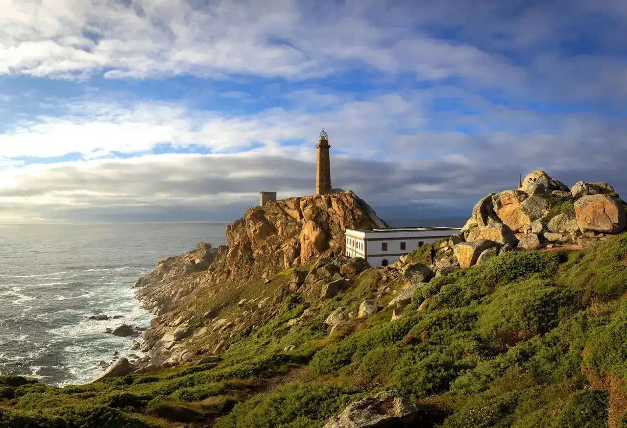 Faro de Finisterre, una estaca de bares en la costa gallega, vigila el Atlántico. Rocas, mar y cielo azul.