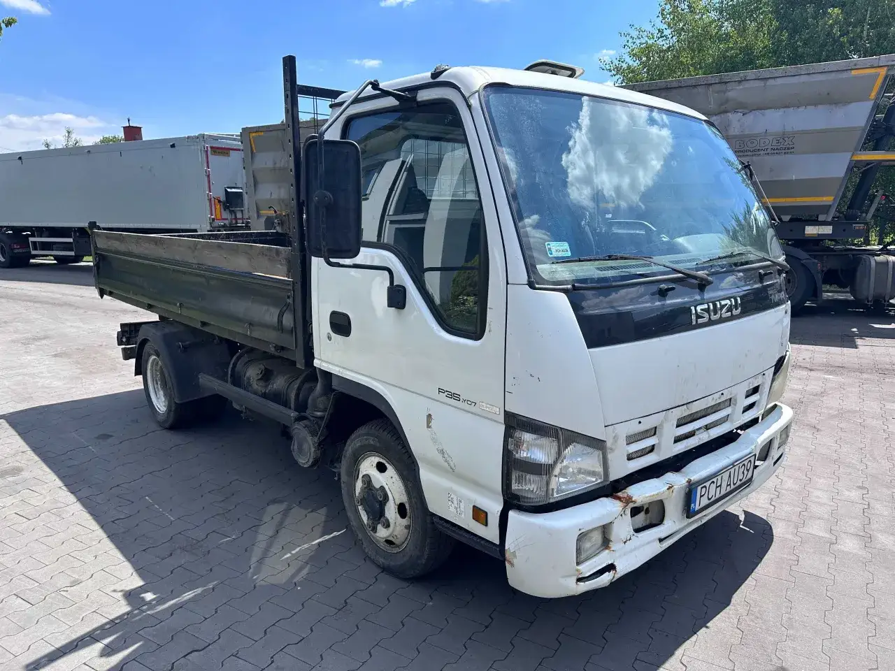 Biała wywrotka Isuzu do 3,5 tony gotowa do pracy. Idealna do transportu materiałów budowlanych.