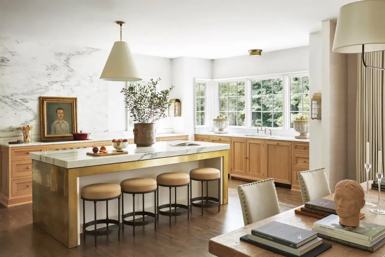 Cocinas sin muebles altos, con isla central de m&aacute;rmol y taburetes. Encimeras de madera y pared de m&aacute;rmol con retrato.