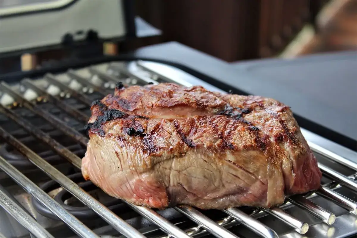 Ein saftiges Steak wird auf einem Grill zubereitet. Die Grillstreifen sind deutlich sichtbar und das Fleisch ist perfekt gebr&auml;unt.
