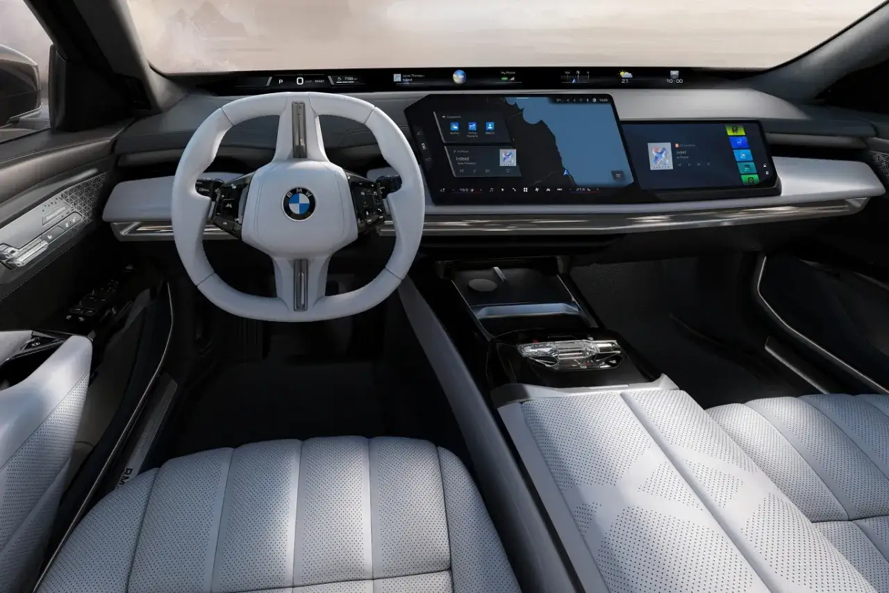 Wnętrze BMW 7 2025: biała skórzana tapicerka, duży ekran multimedialny i nowoczesna kierownica.