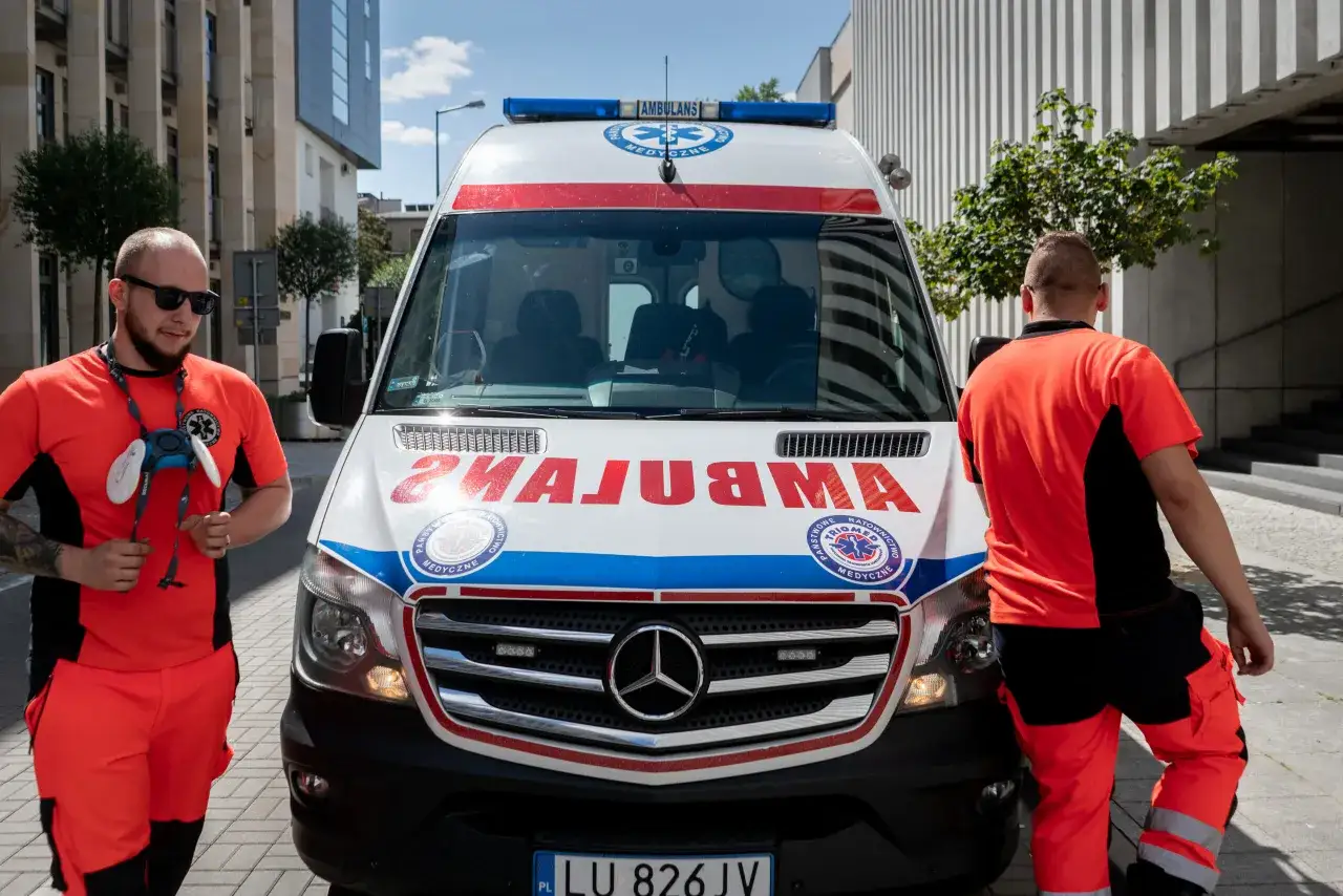 Dwóch ratowników w pomarańczowych strojach stoi obok karetki. Zastanawiasz się, ile zarabia kierowca karetki?