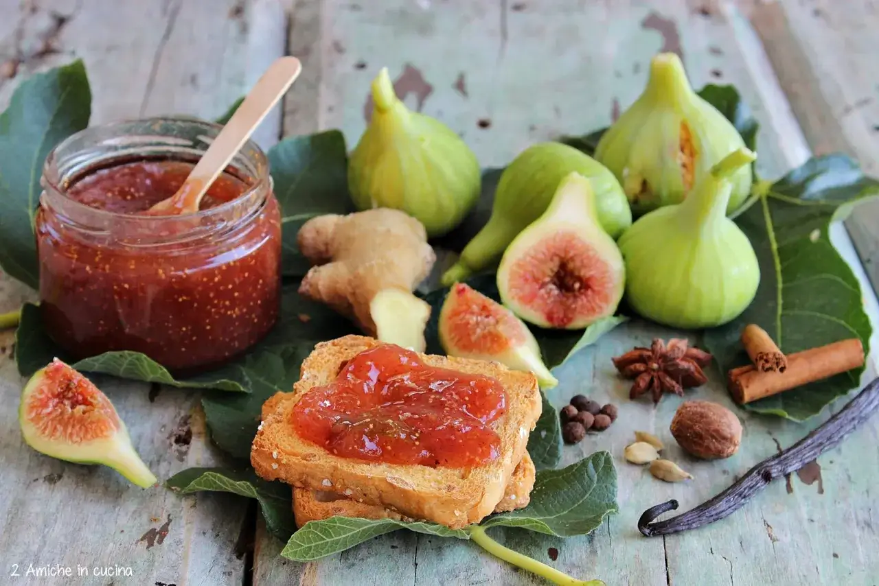 Un vasetto di marmellata di fichi, fichi freschi, zenzero e spezie su foglie verdi.