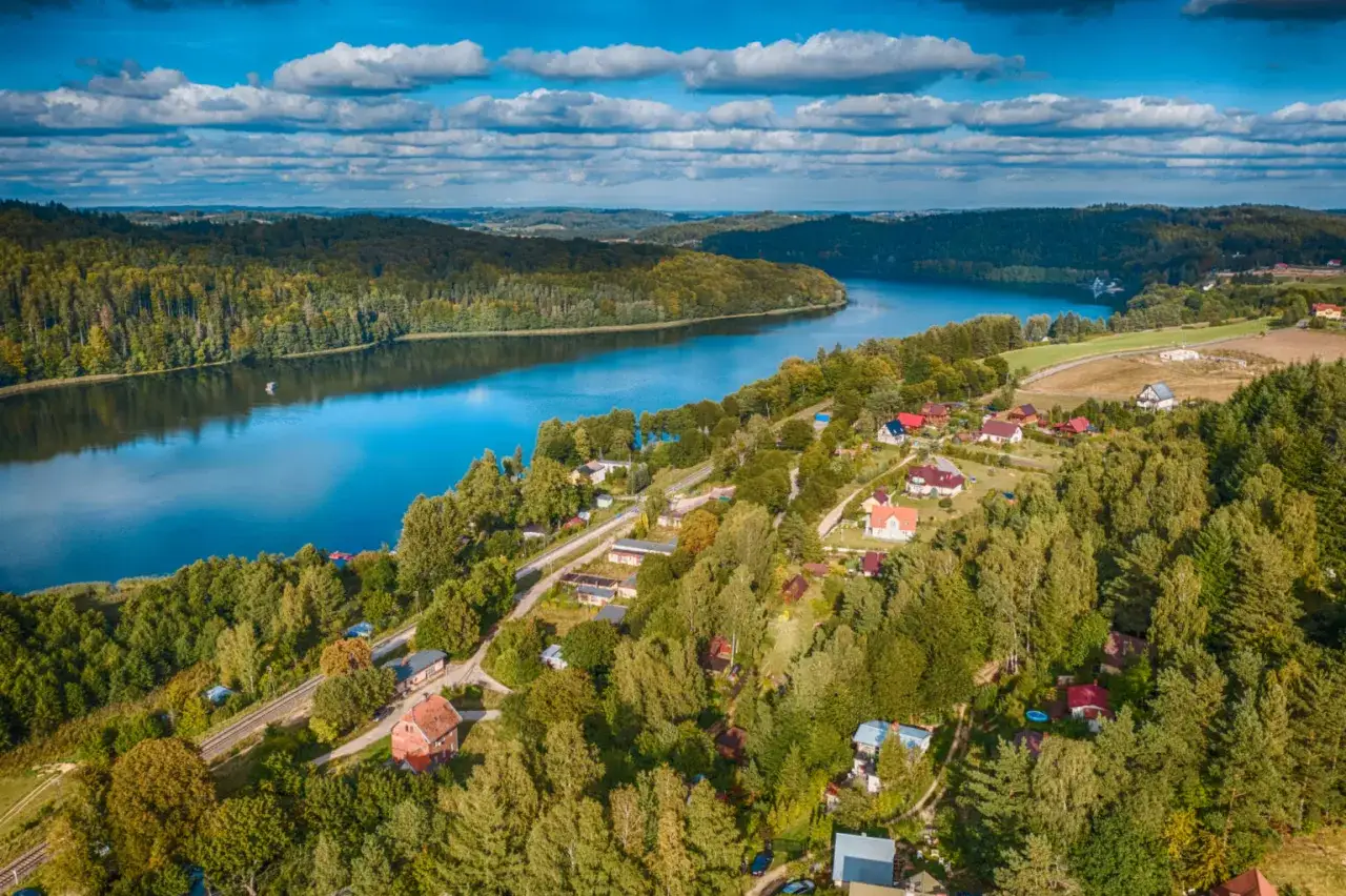 Malownicze jezioro otoczone lasami, z domkami letniskowymi i drogą. To jedno z najpiękniejszych miejsc Kujawsko-Pomorskiego.