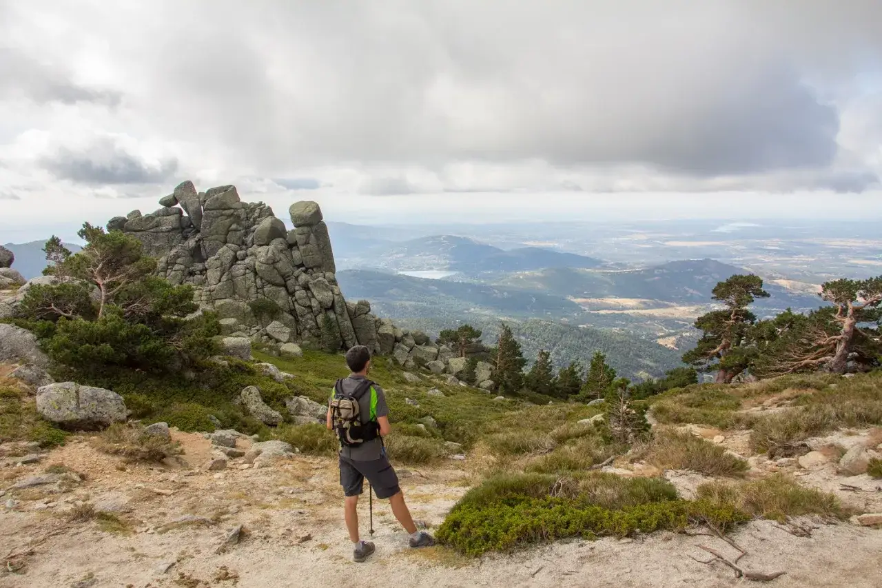 Senderista contempla el paisaje desde la ruta siete picos, con formaciones rocosas y un valle extenso.