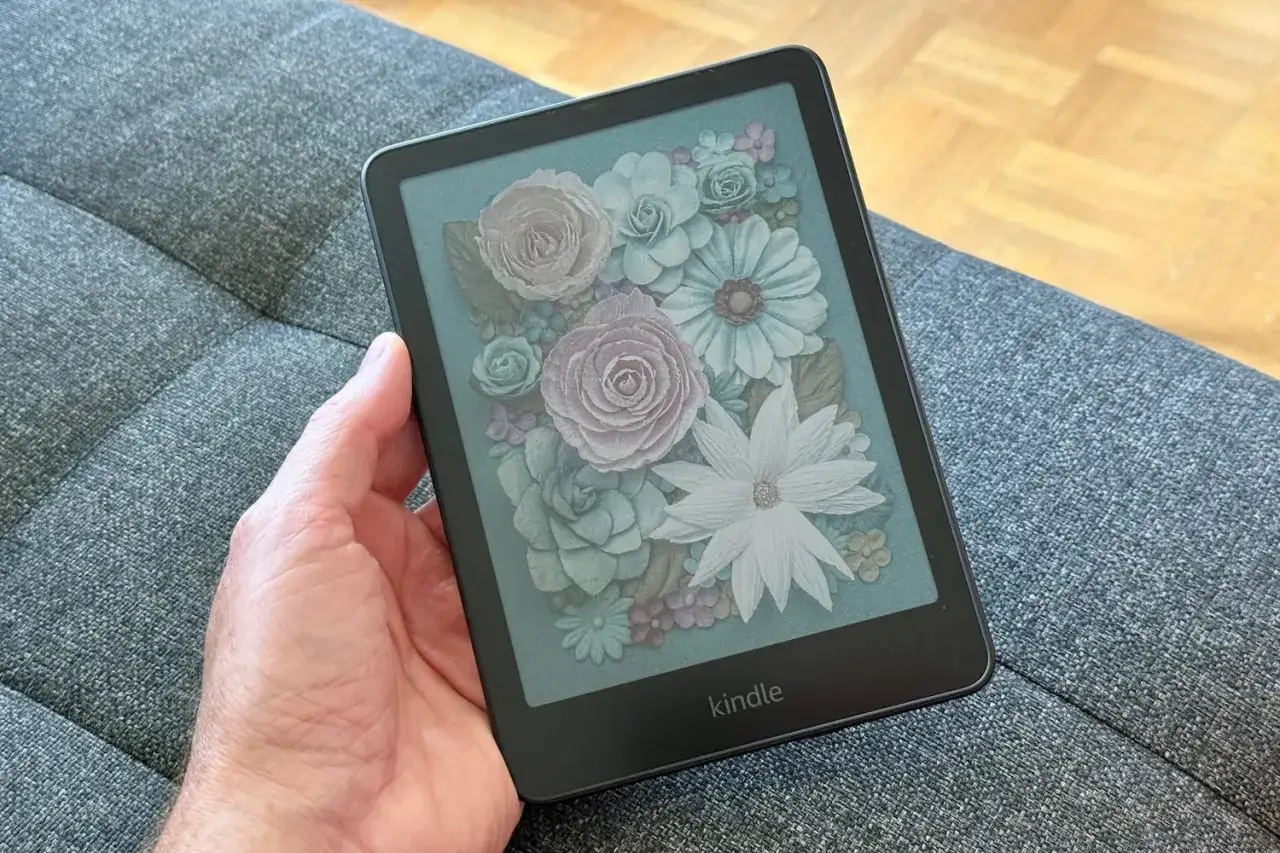 Main tenant une liseuse Kindle avec un écran affichant un bouquet de fleurs stylisées. Ce visuel peut servir de guide pour le kindle mode d'emploi.