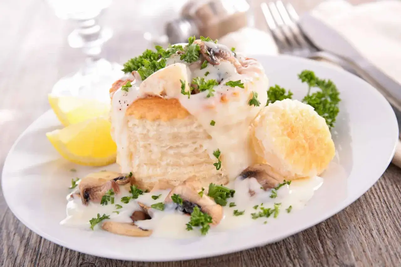 Un d&eacute;licieux vol au vent poulet, garni de champignons et de persil frais, servi avec des quartiers de citron.