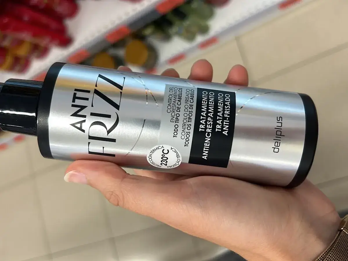 Mano sostiene botella de tratamiento anti-frizz Deliplus de Mercadona. Buscando opiniones sobre este producto anti frizz Mercadona.