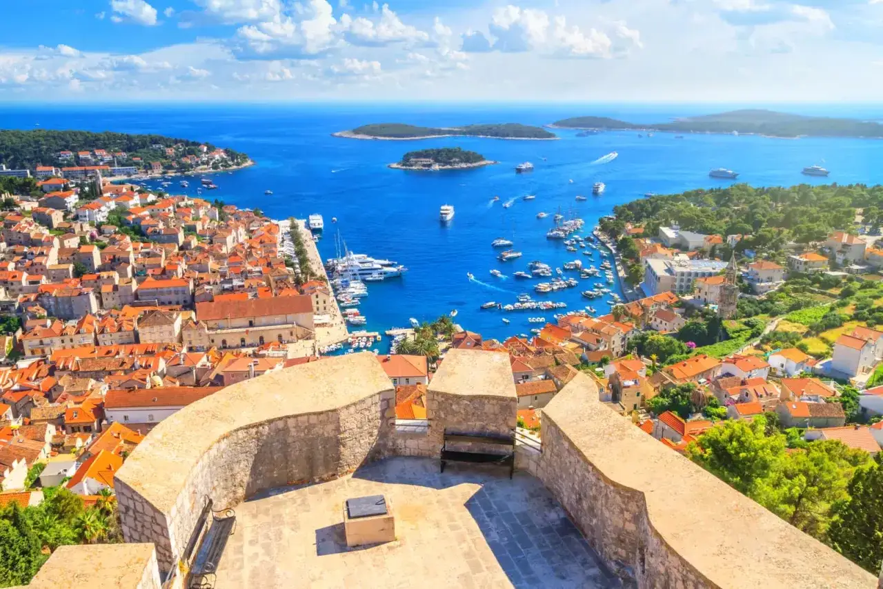 Widok na Hvar, **najpiękniejszą wyspę Chorwacji**, z zatoką pełną łodzi i błękitnym morzem.