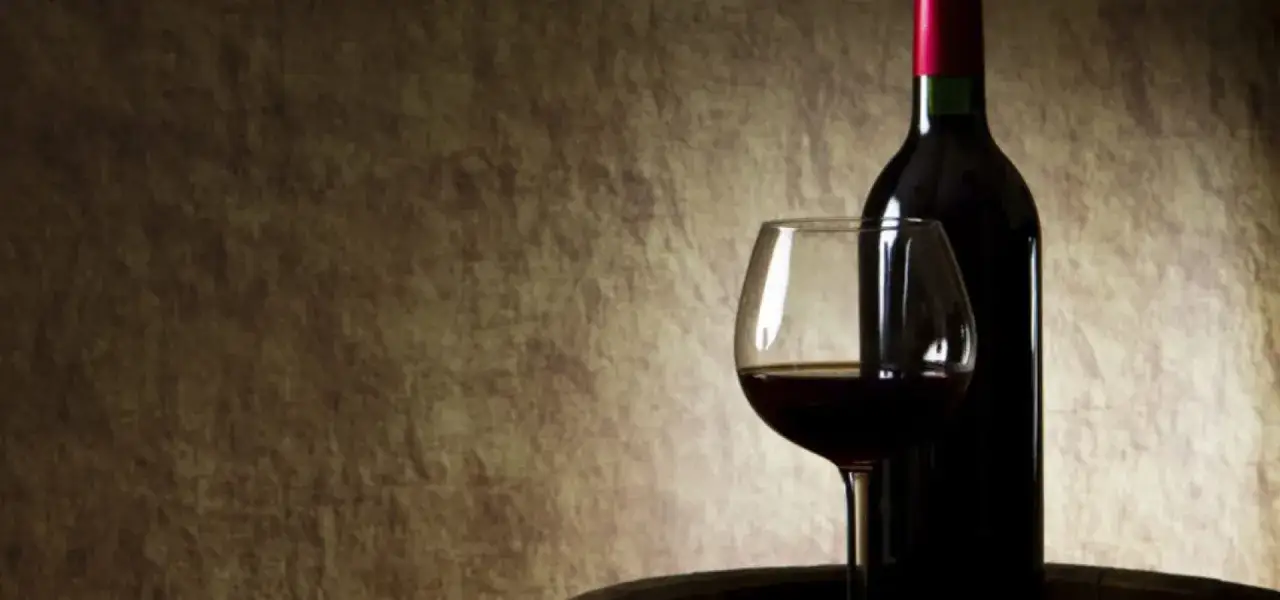 Butelka i kieliszek z czerwonym winem na tle. Czy czerwone wino się chłodzi?