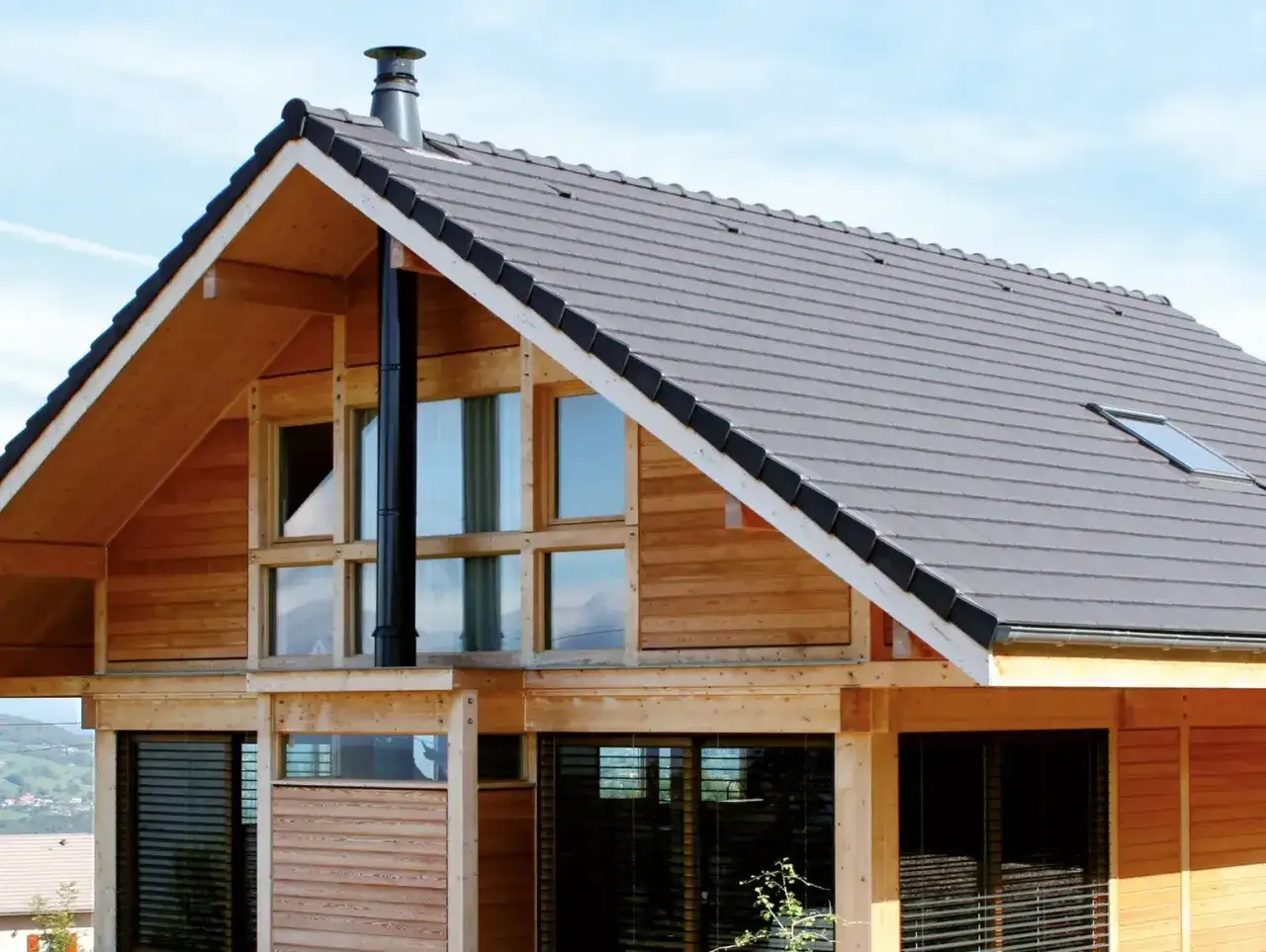 Drewniany dom z dużymi oknami i czarnym kominem. Czy potrzebne jest pozwolenie na budowę komina?
