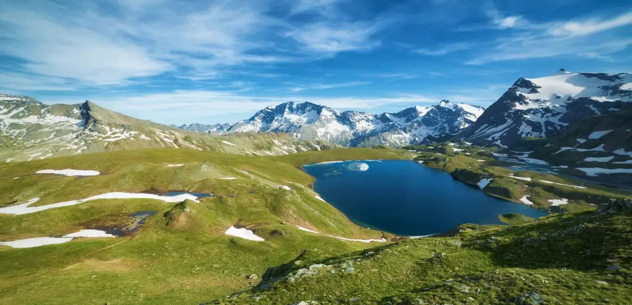 Un lac bleu profond refl&egrave;te le ciel azur, entour&eacute; de montagnes enneig&eacute;es et de prairies verdoyantes. Un paysage d'une beaut&eacute; &agrave; couper le souffle, un v&eacute;ritable grand paradis.