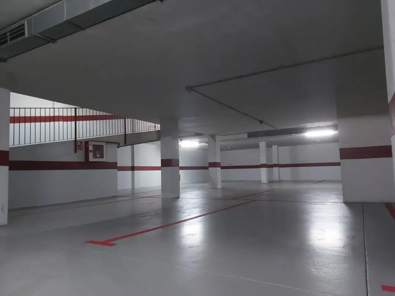 Suelo de garaje recién pintado con líneas rojas, listo para estacionar.