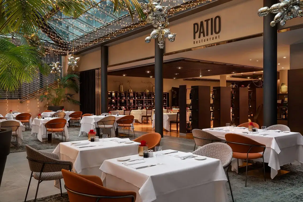 Atmosfera elegante al Patio Restaurant, un'ottima opzione per chi cerca dove mangiare a Bolzano. Tavoli apparecchiati con cura sotto luci soffuse.