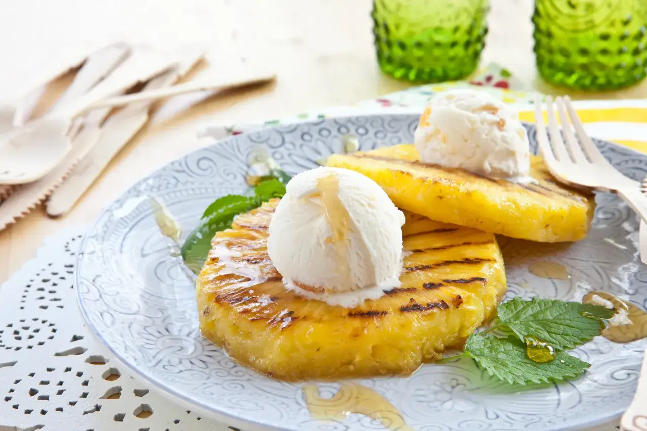 Grillowany ananas z lodami waniliowymi, polany miodem, to idealny deser na grilla.