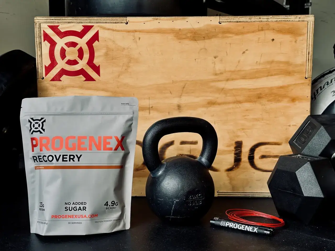 Torba z suplementami na regenerację Progenex, kettlebell i hantle. Idealny zestaw dla sportowców.