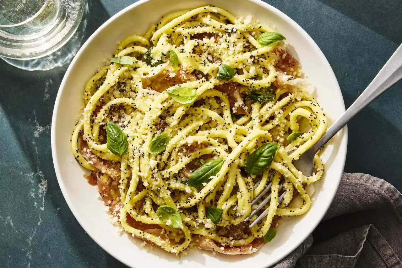 Teller mit Spaghetti mit Zitronensauce, garniert mit Basilikum und geriebenem K&auml;se. Ein Hauch von Mohn sorgt f&uuml;r Textur.