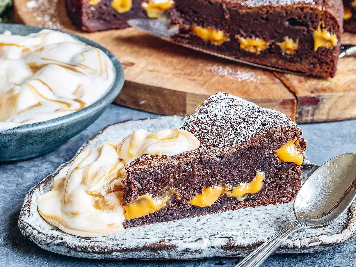 En saftig kladdkaka med len dulce de leche-fyllning, pudrad med florsocker och serverad med vispad gr&auml;dde.