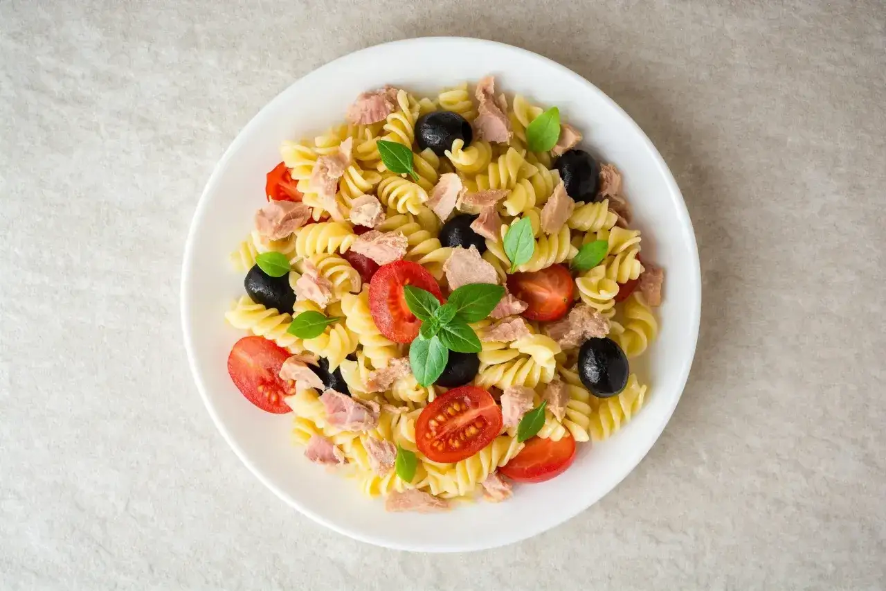Une d&eacute;licieuse salade de p&acirc;tes fusilli garnie de thon, tomates cerises, olives noires et basilic frais.