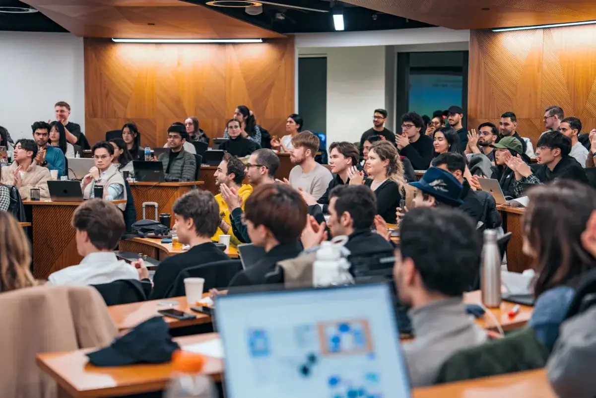 Students in a classroom setting, some clapping, others listening intently. This scene could be part of a discussion on mba vs masters in leadership programs.