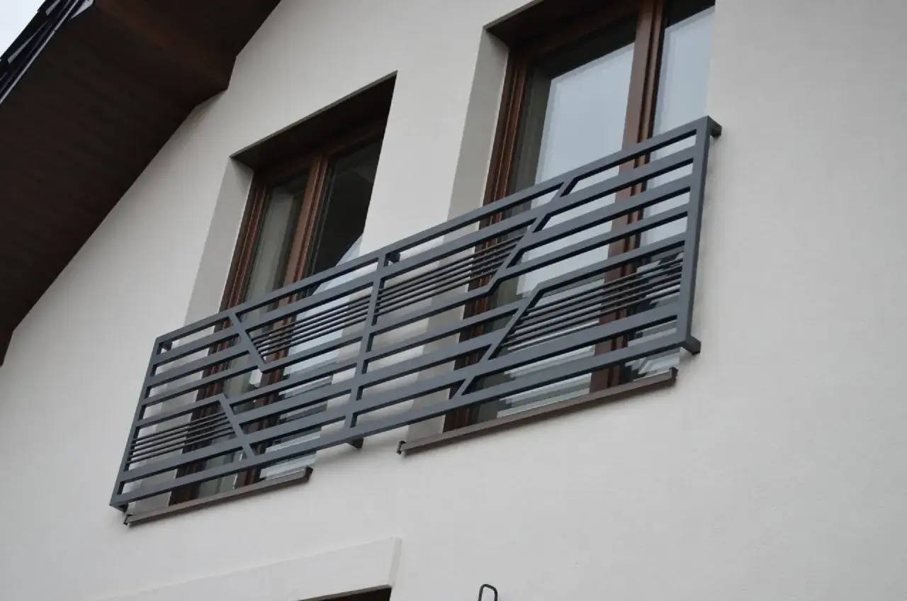 Nowoczesne balkony francuskie z metalową, geometryczną balustradą zdobią elewację domu.