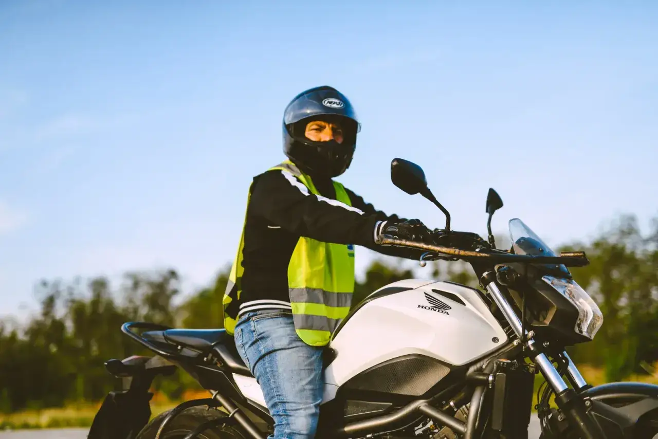Mężczyzna w kasku i kamizelce odblaskowej siedzi na motocyklu Honda. Zastanawia się nad prawem jazdy A2 cena.