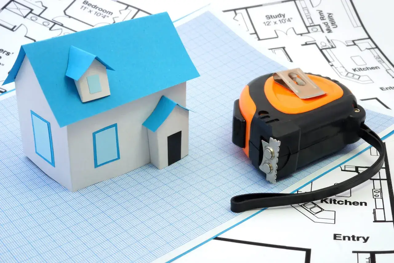 Modello di casa e metro su planimetrie. Pianificare come mantenere detrazioni fiscali dopo vendita immobile.