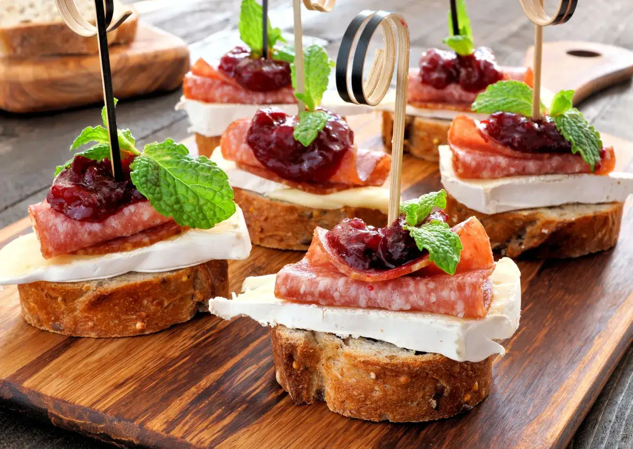 Deliziosi crostini con salame, il brie è un formaggio grasso, marmellata di frutti rossi e menta fresca.