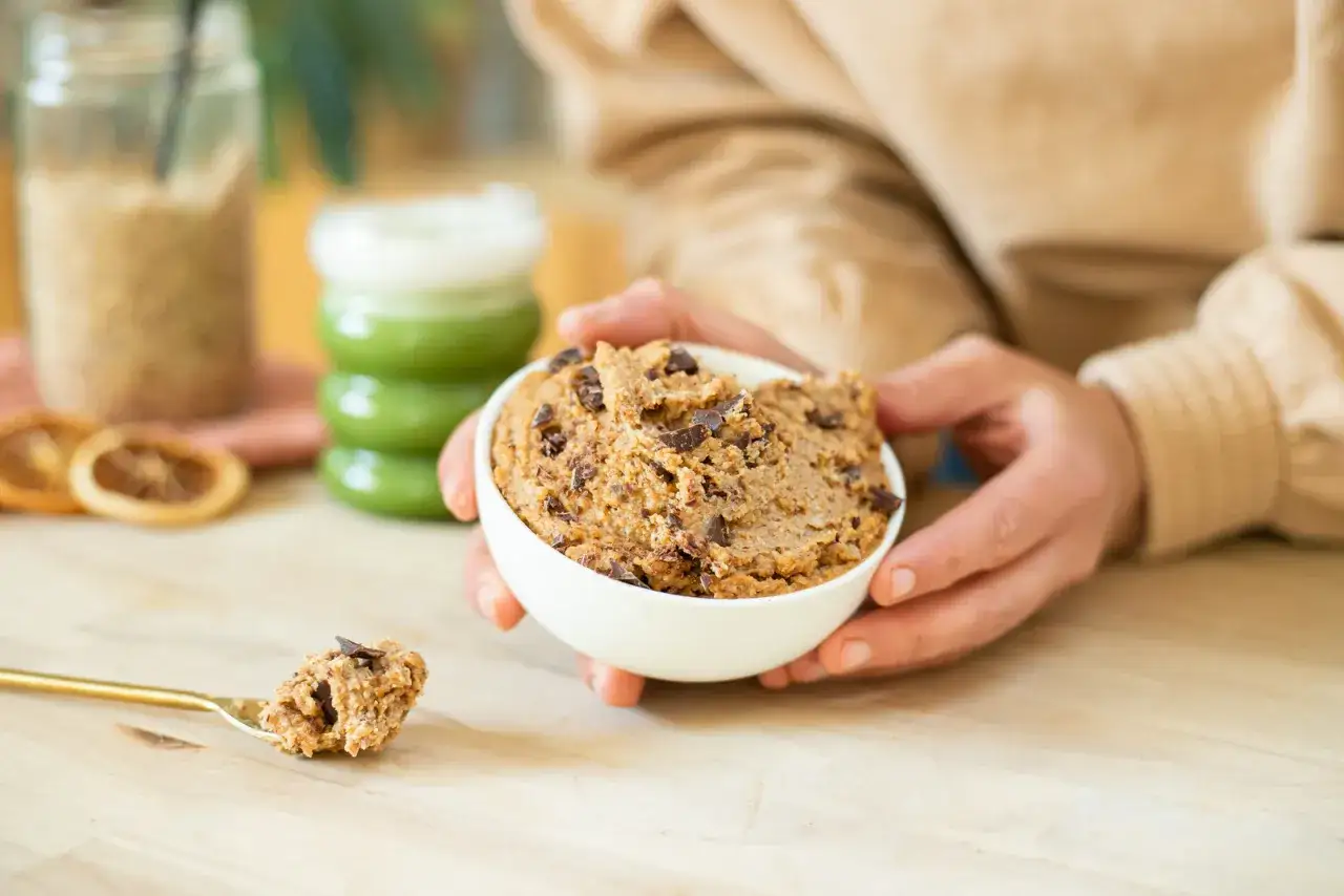 Un bol de cookie dough pois chiche, parsemé de pépites de chocolat, prêt à être dégusté.