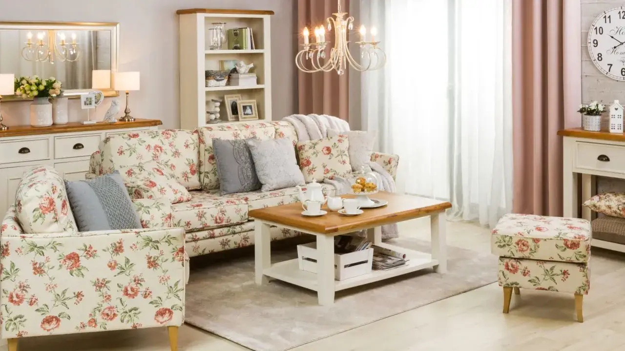 Przytulny salon w stylu shabby chic. Kwiecista sofa, stolik kawowy z ciasteczkami i pastelowe zasłony tworzą romantyczny nastr&oacute;j.