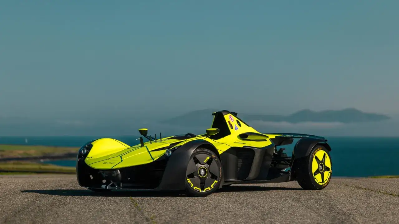 Jaskrawożółty bolid BAC Mono z czarnymi akcentami na tle błękitnego nieba i morza.