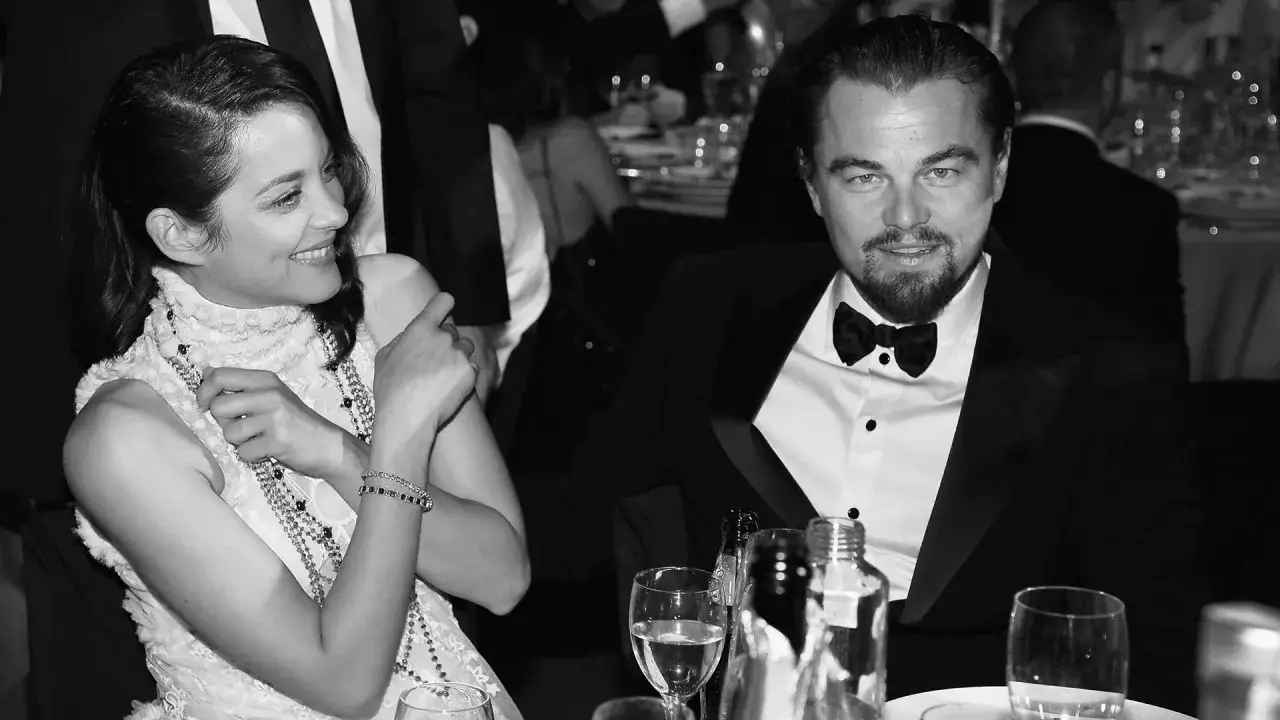 Leonardo DiCaprio and Marion Cotillard at an event. He's wearing a tuxedo with shirt studs, a classic look.