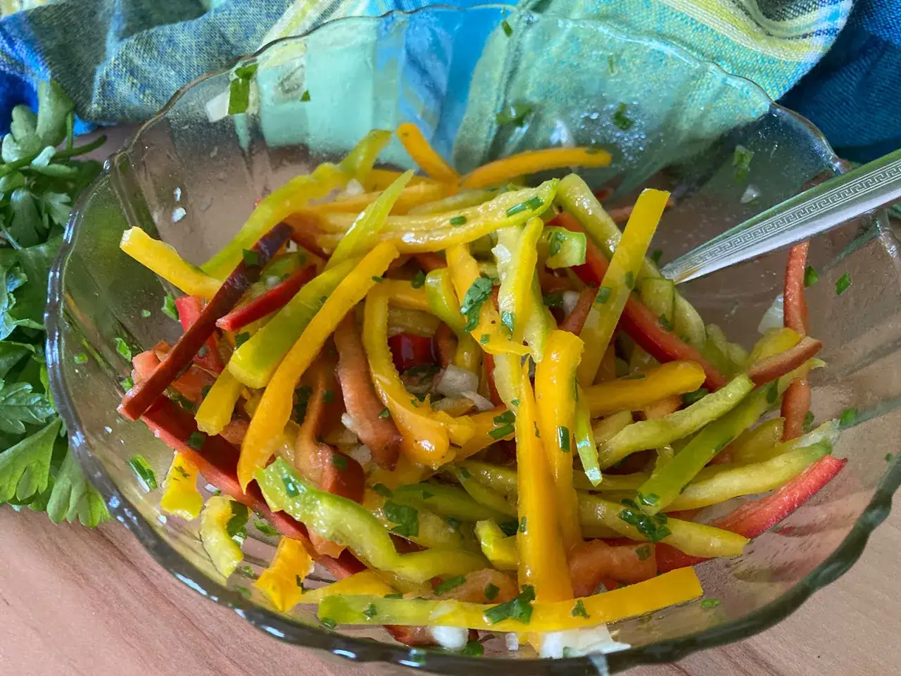 Bunter Salat aus geschnittenen Paprika in Gelb, Grün und Rot, garniert mit Kräutern.
