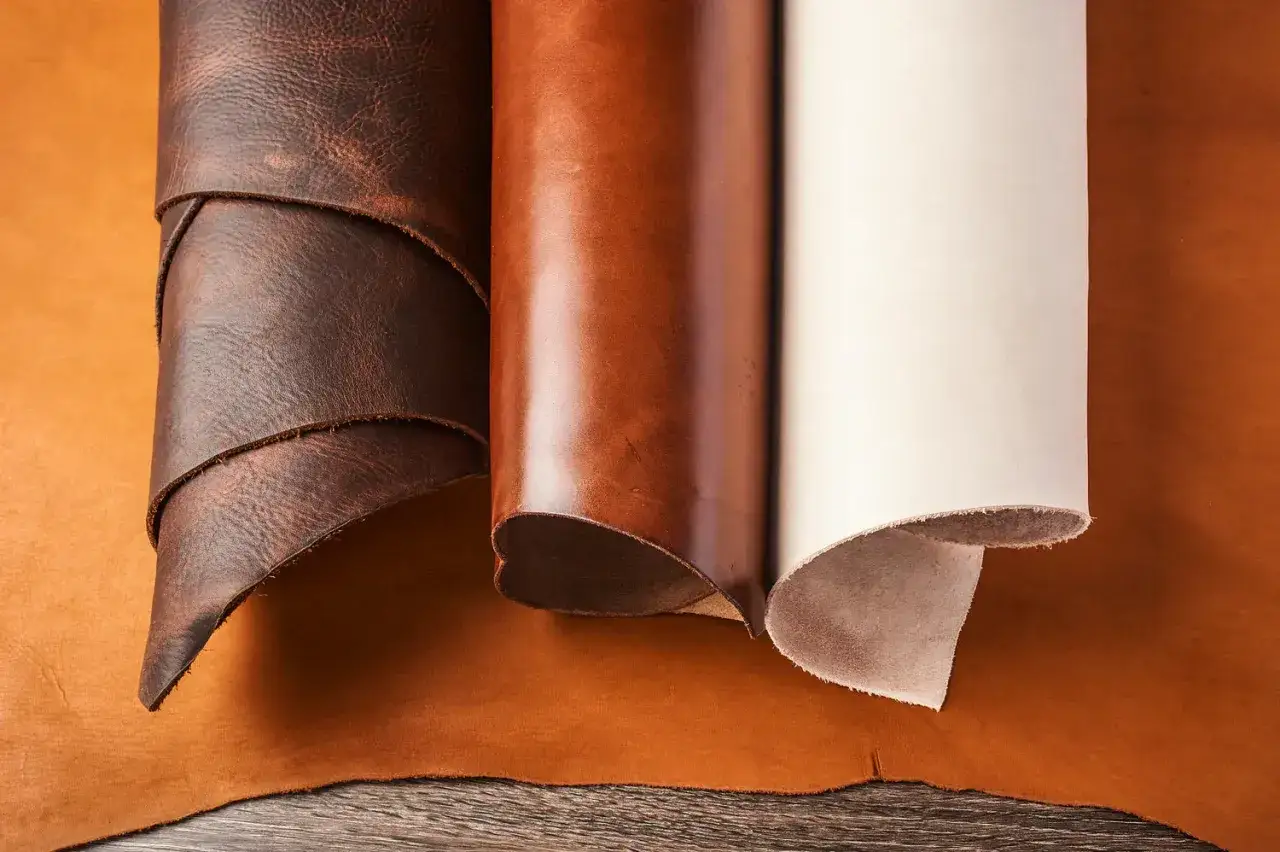 Trois rouleaux de cuir aux teintes variées, du brun foncé au blanc cassé, témoignent du savoir-faire du tannage du cuir.