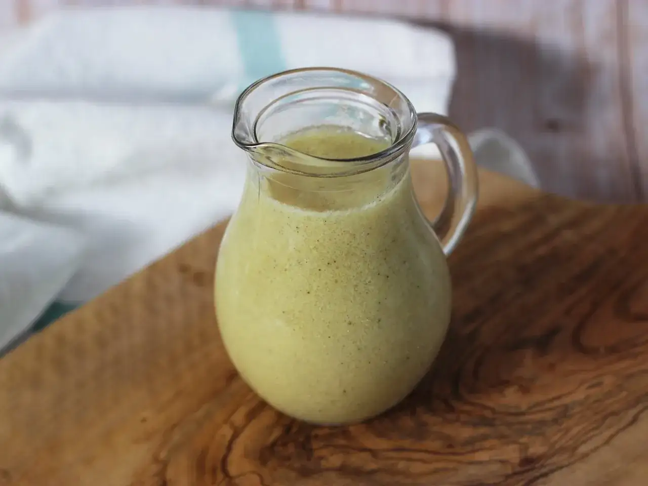 Ein Krug mit cremiger Vinaigrette steht auf einem Holzbrett. Perfekt f&uuml;r Salate!
