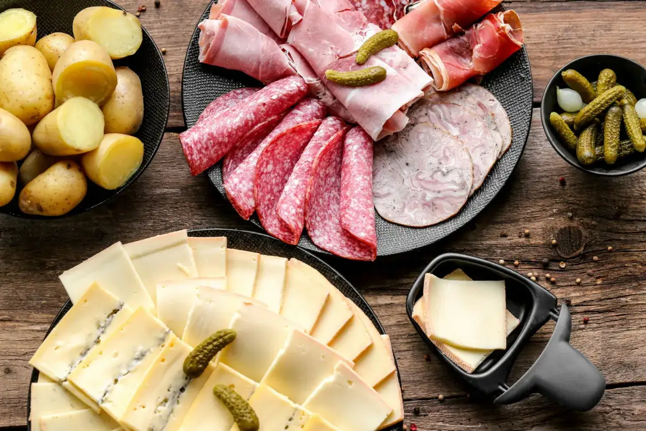 Un plateau de charcuterie et de fromages pour la raclette, avec pommes de terre, cornichons et saucisson.